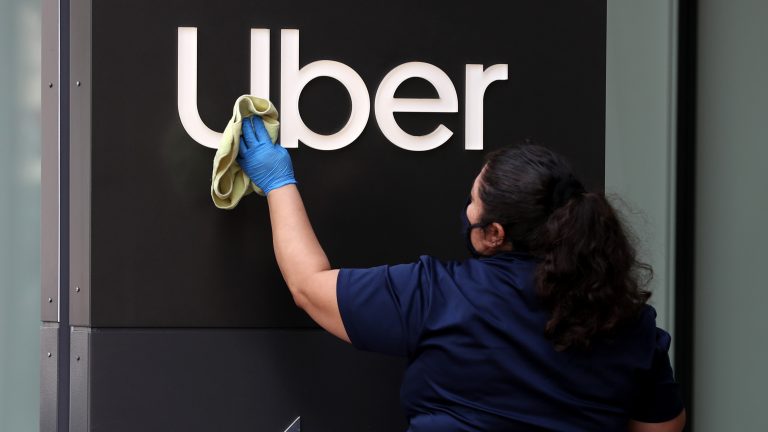 A worker cleans a sign in front of the Uber headquarters