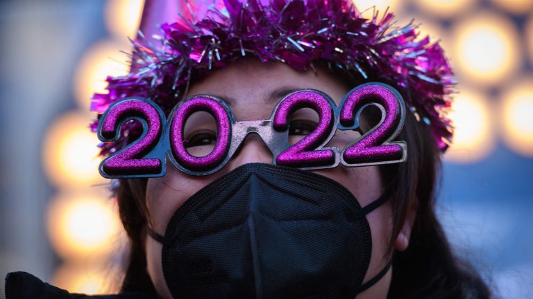 A woman wearings glasses in the shape of 2022.