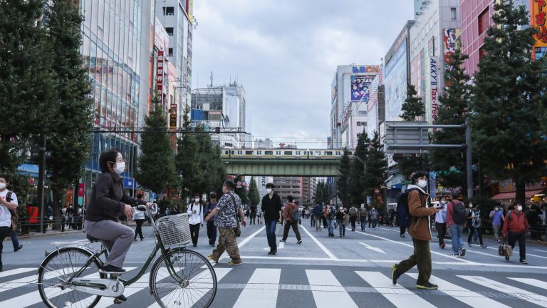 People walk and ride through the streets of Akihabara.