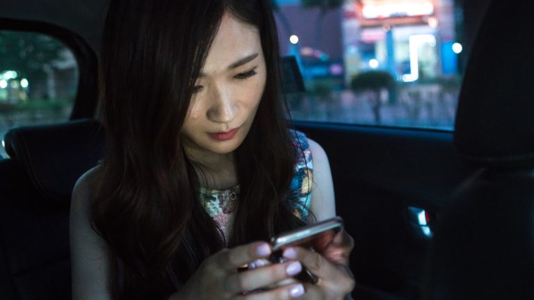 A woman reading text messages on her mobile phone in South Korea.