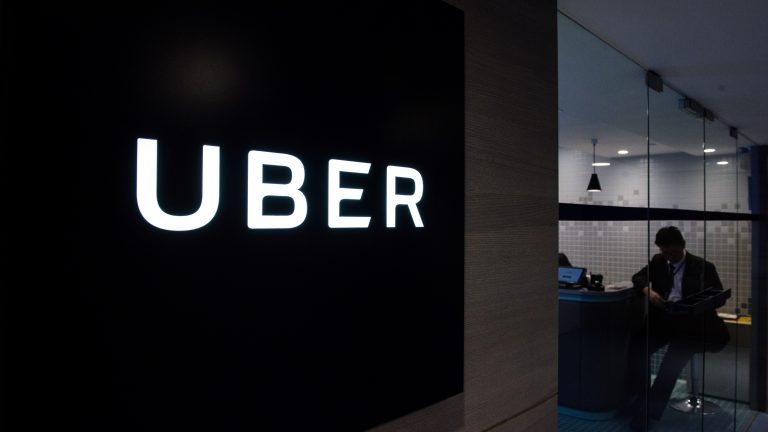 Uber signage is seen as an employee sits in an entrance to one of the ride-hailing giant office.