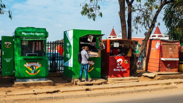 A customer talks to a vendor at a mobile phone money agent booth in Lilongwe, Malawi.