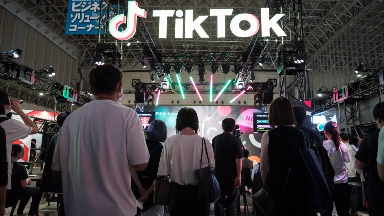 Attendees stand under a large TikTok sign at a booth at an event.