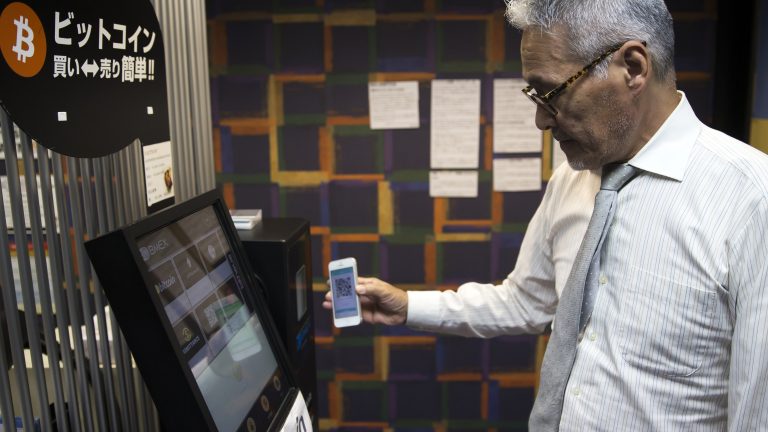 A man demonstrates the use of a bitcoin automated teller machine (ATM) in Japan.