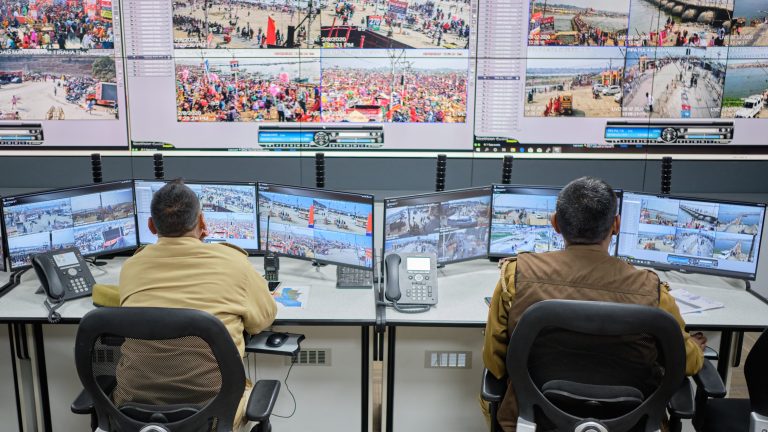 Two police officers watch CCTV cameras during an event in India.
