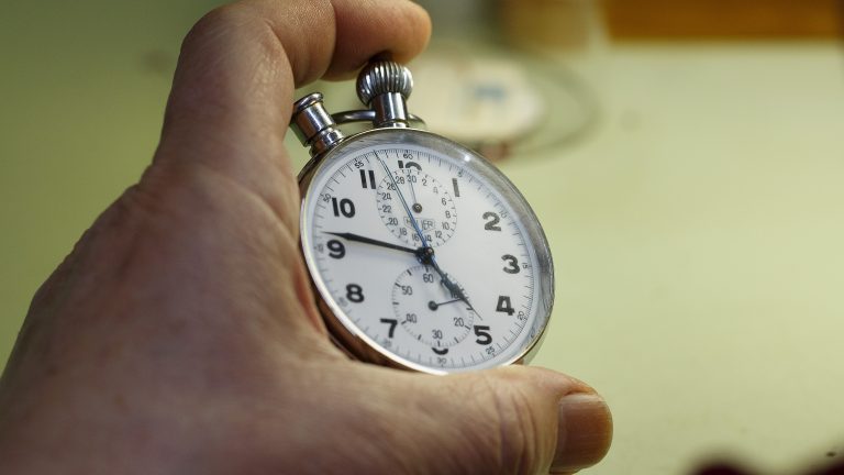 A man uses a pocket watch to check the time.