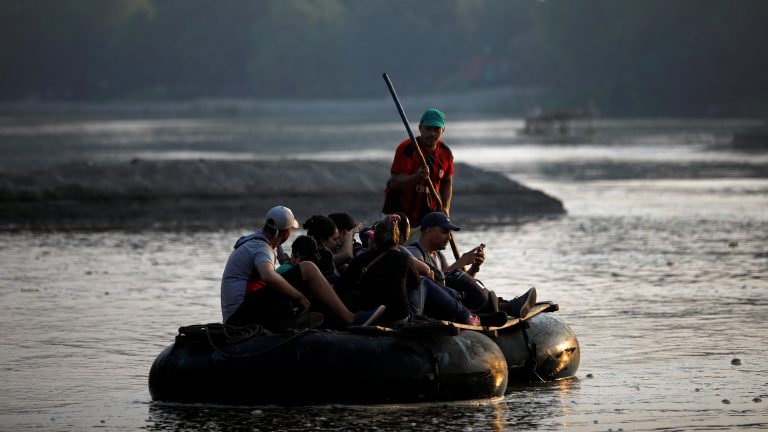 A photo of migrants on a rubber rafts crossing a body of water.