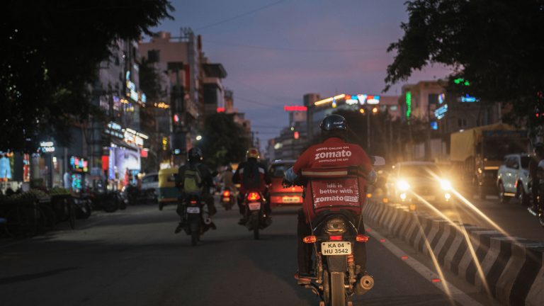 A photo of a Zomato delivery rider taken from behind the motorbike.