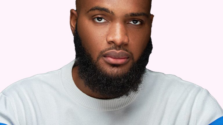 A headshot of Nigerian Youtuber Tayo Aina, against a light pink background.