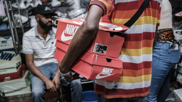 A photo showing a person from behind, holding two red Nike shoe boxes inside a store.