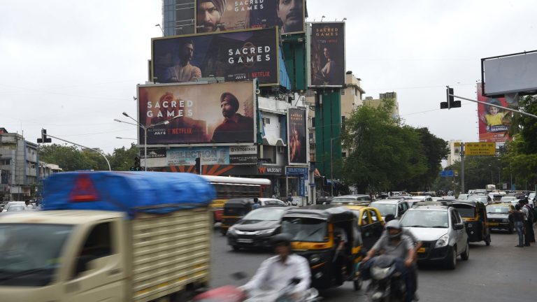 Commuters drive along a road past a billboard advertising Netflix.