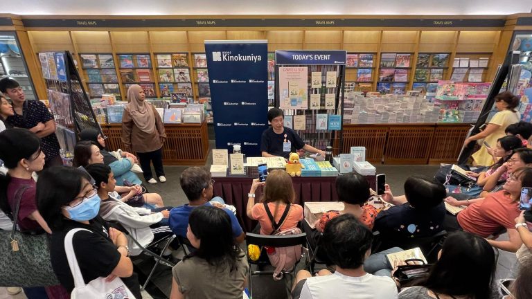 Singaporean author and poet Gwee Li Sui surrounded by an audience at an event inside a bookstore.