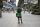 A photo of a Grab food delivery rider standing with their back to the camera in the middle of an empty city scape.